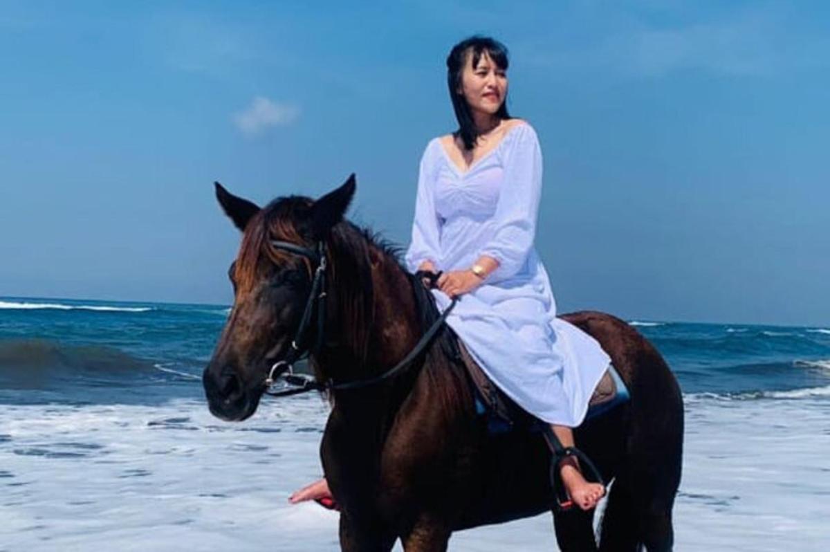 a woman riding a horse on the beach