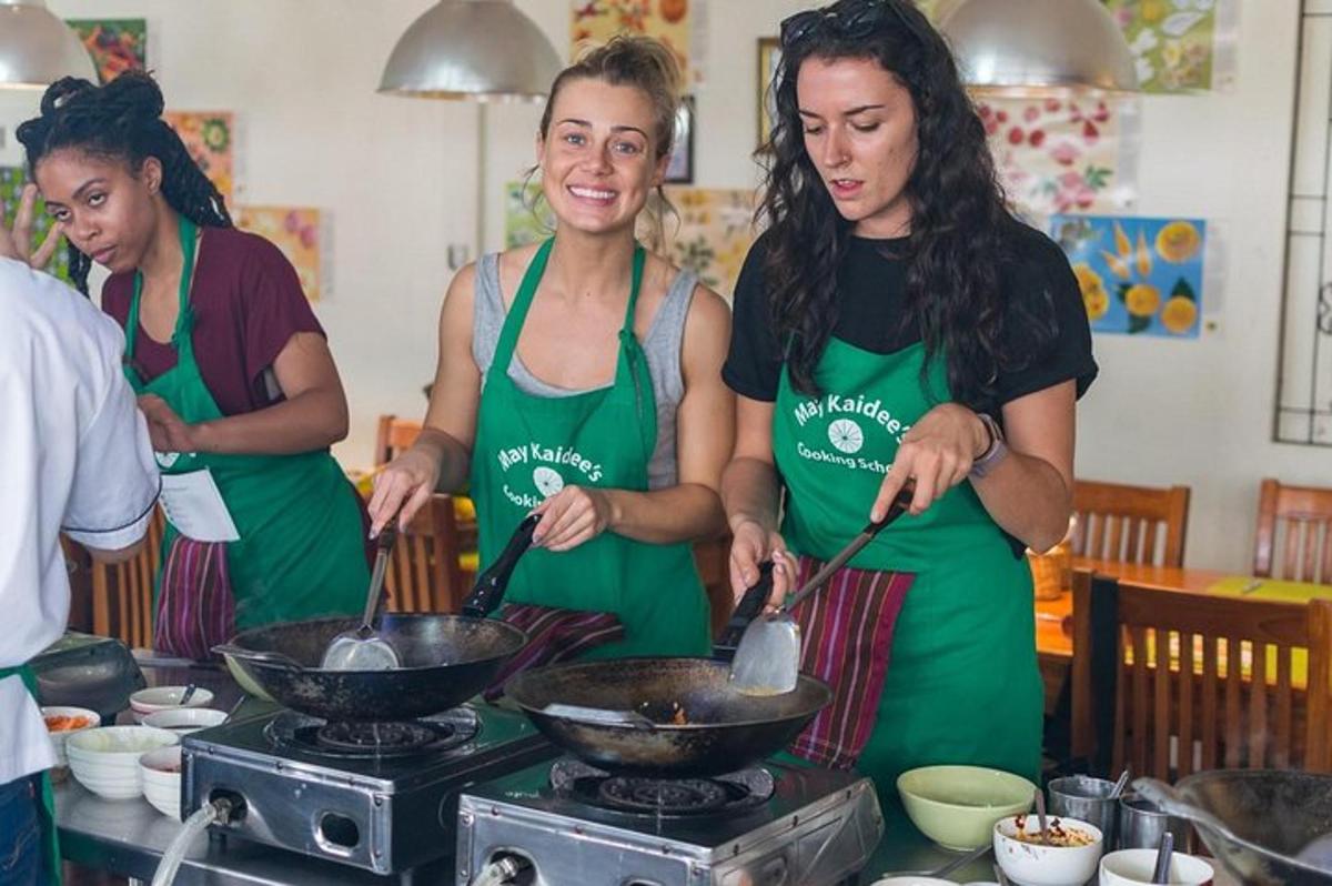 Þrjár konur í eldhúsi að útbúa mat í wok-pönnu