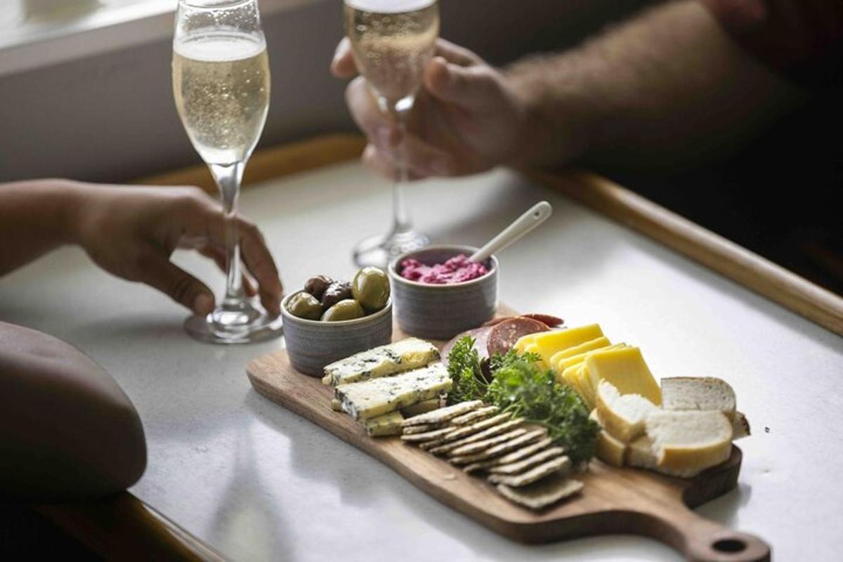 un piatto di formaggio e pane e due persone con bicchieri di champagne