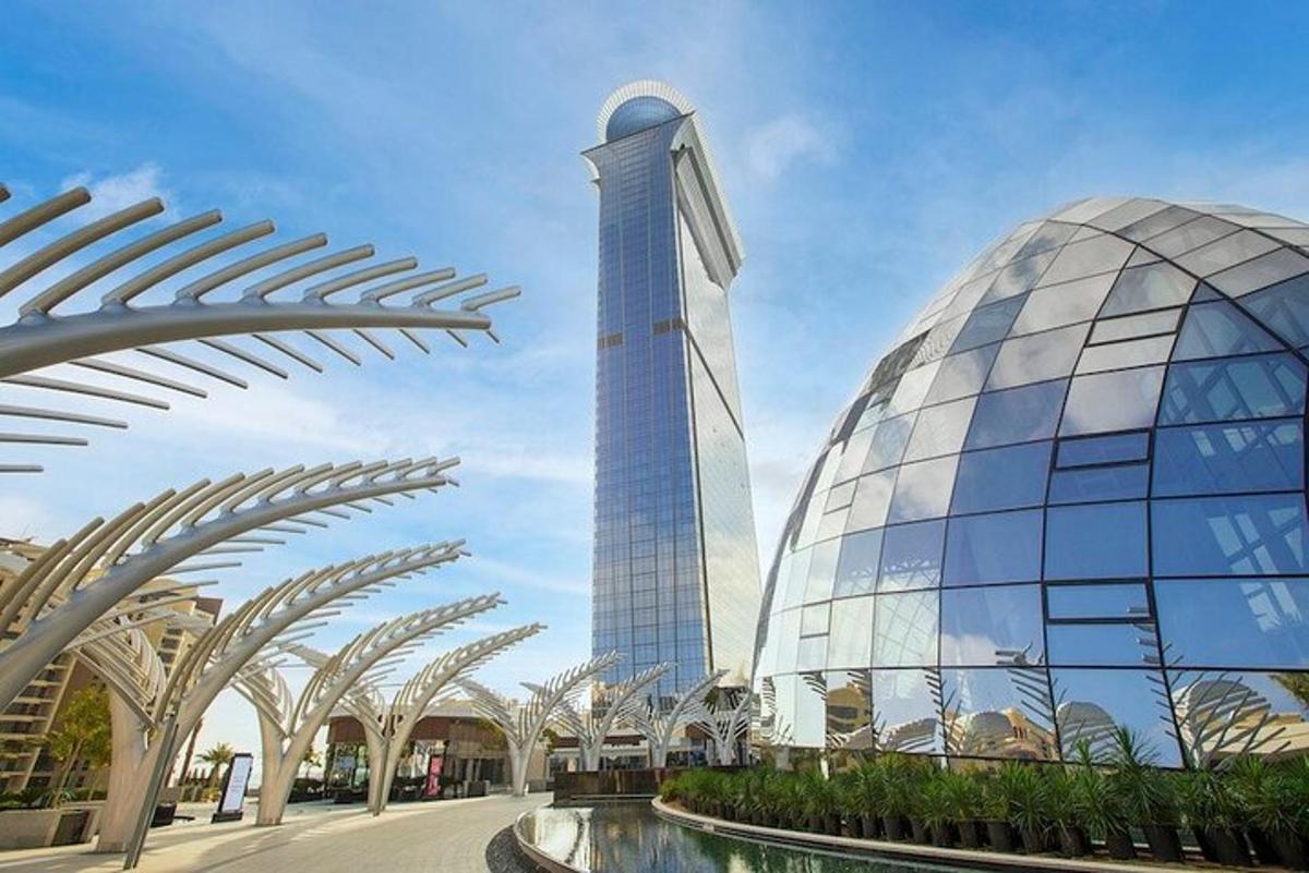 a large glass building with a tower in the background