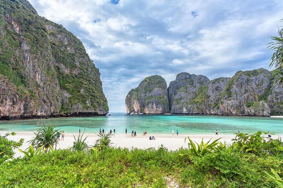 sekumpulan manusia di pantai dengan tebing batu kapur