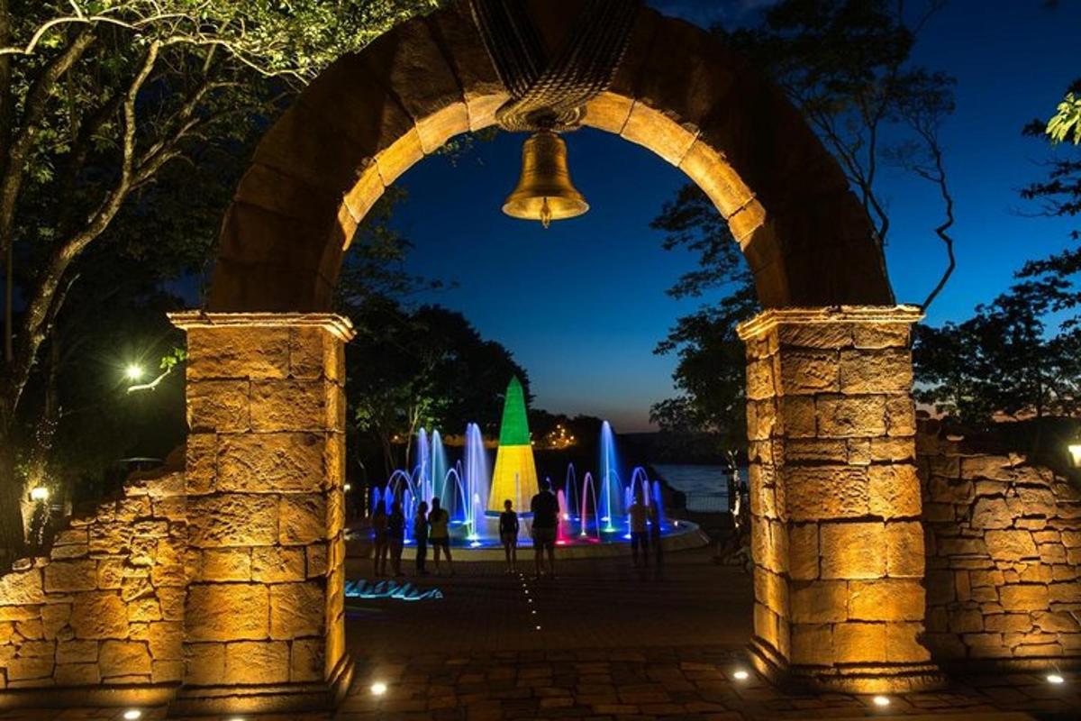 an archway with a fountain in a park at night
