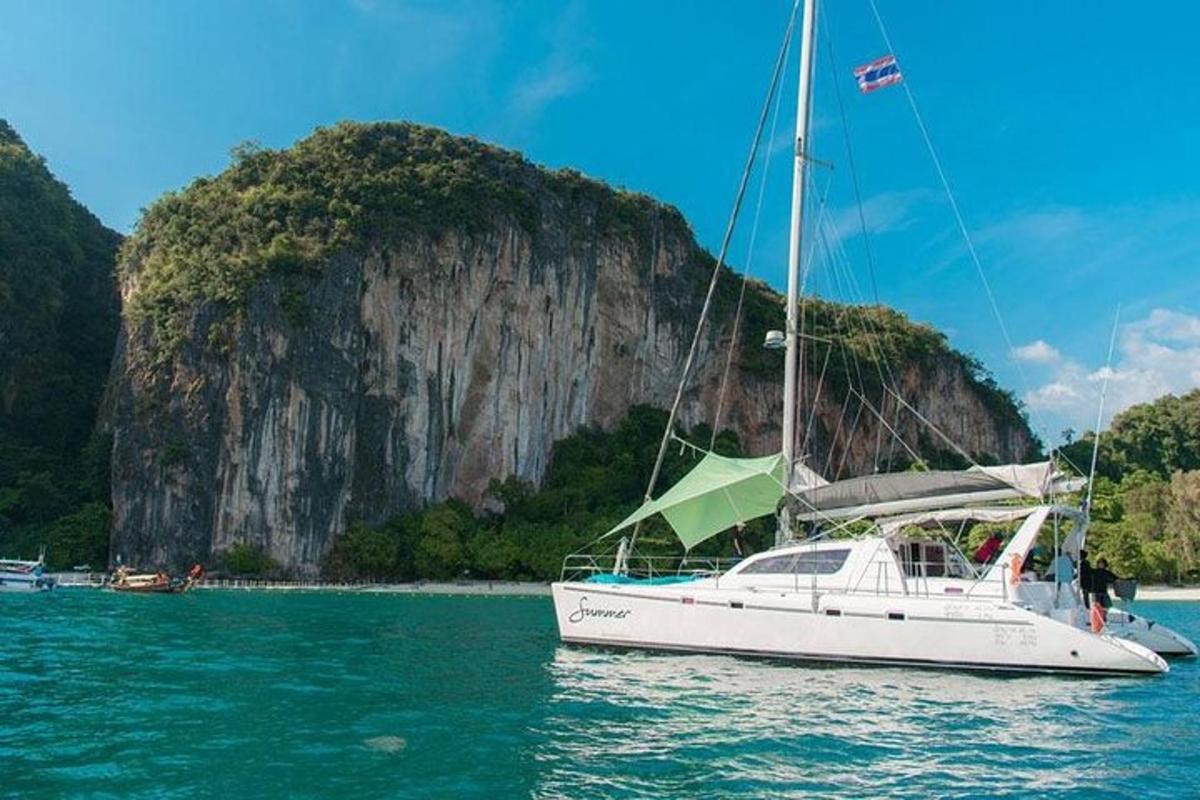 a white sail boat in the water with a mountain