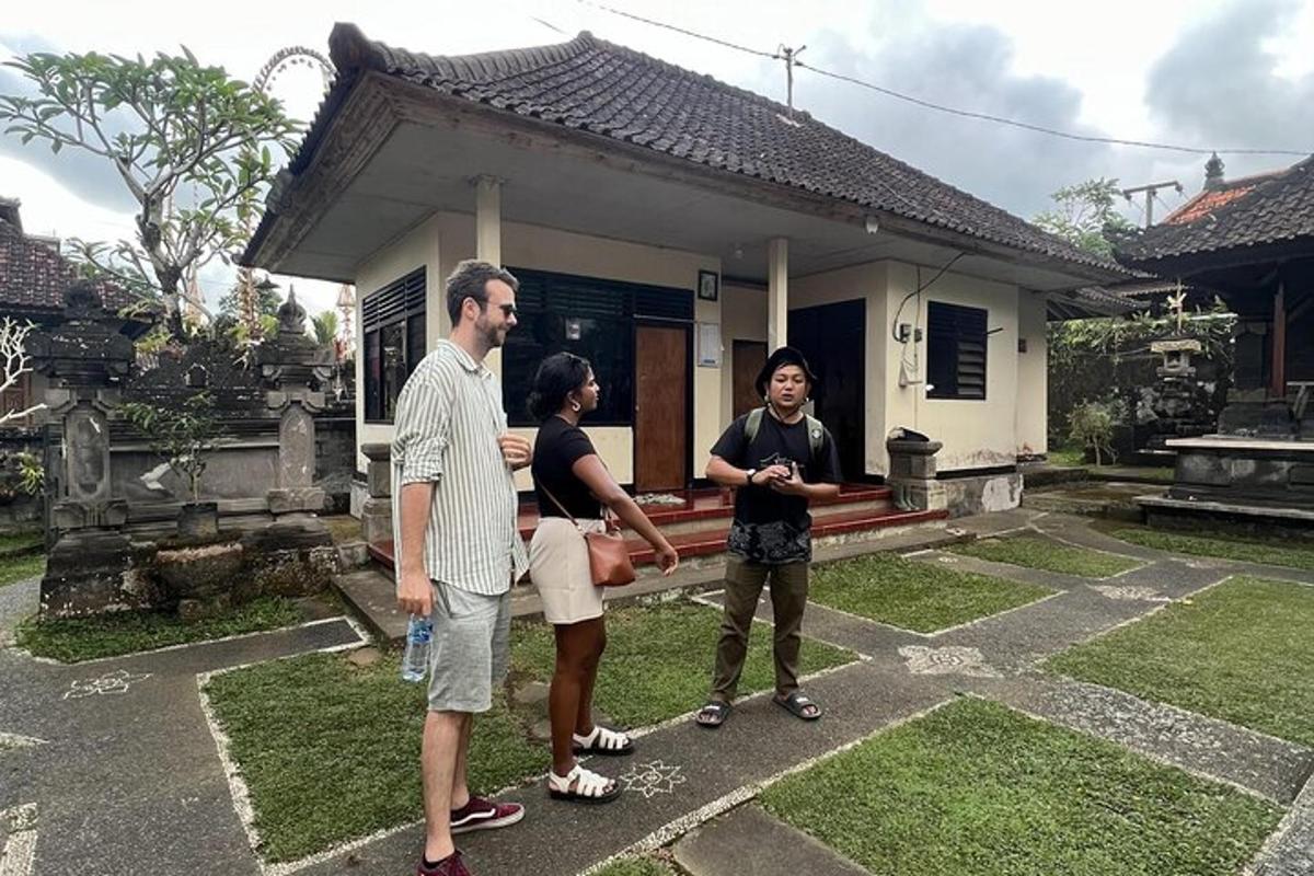 três pessoas em pé em frente a uma pequena casa