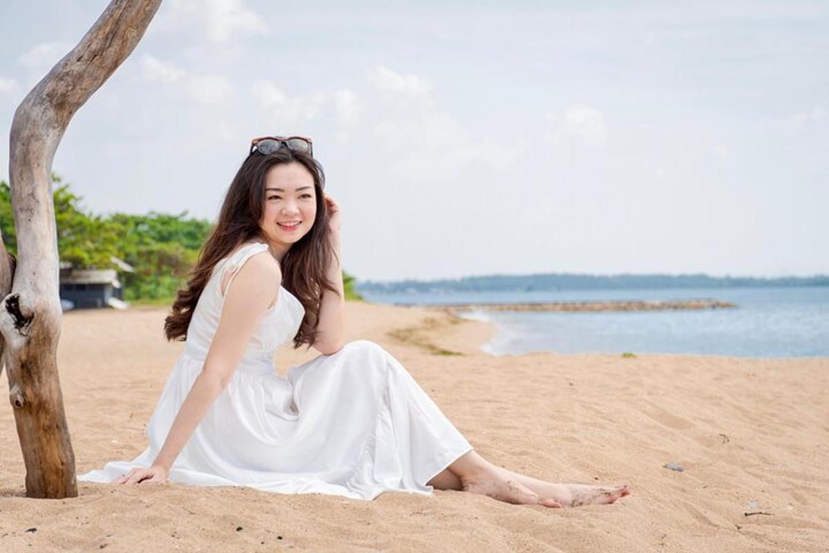 một người phụ nữ mặc váy trắng đang ngồi trên bãi biển