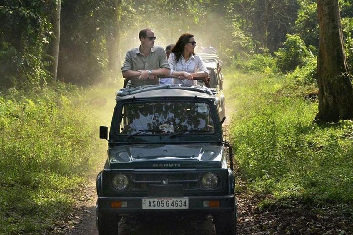 two people riding in the back of a jeep on a dirt road