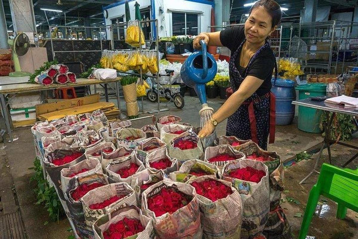Una mujer parada frente a un arreglo floral.