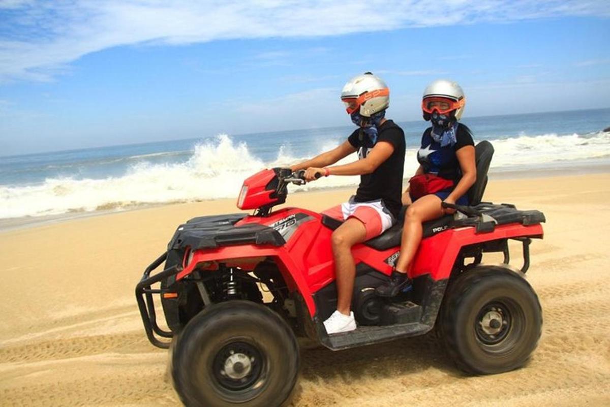 dua orang mengendarai sepeda quad di pantai