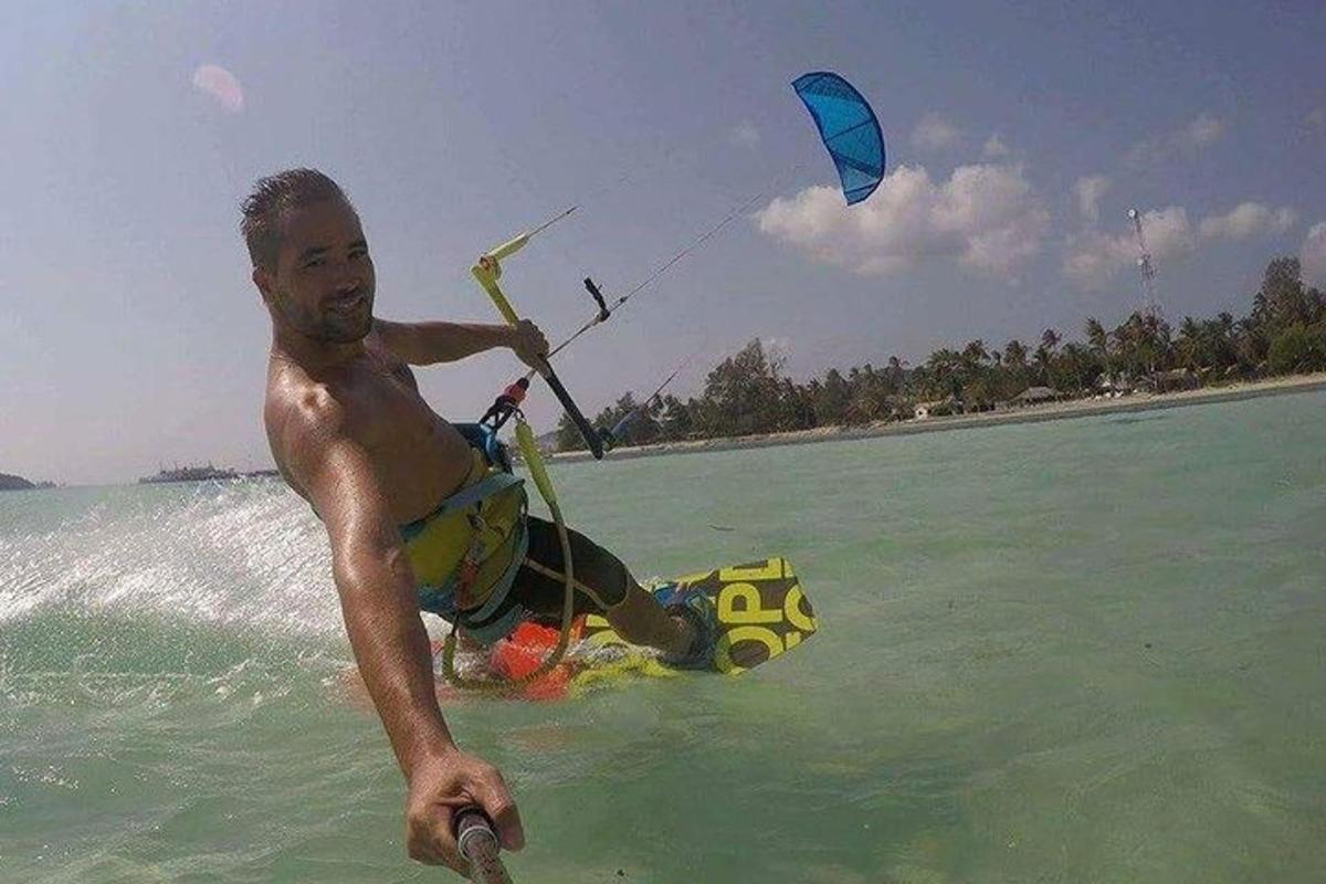 een man in het water met een vlieger in de oceaan