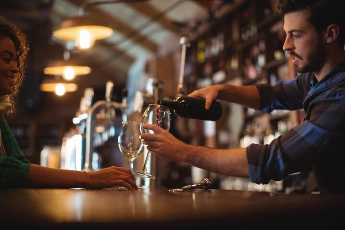 een man die een vrouw een glas inschenkt in een bar