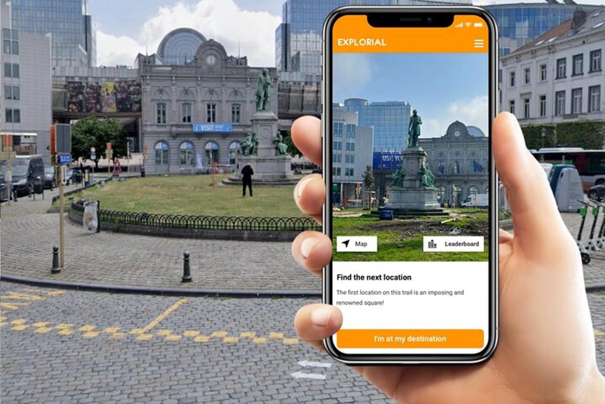 osoba držící mobilní telefon před sochou