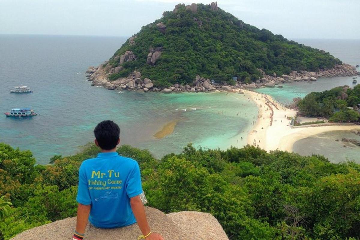 seorang lelaki duduk di atas batu melihat pantai