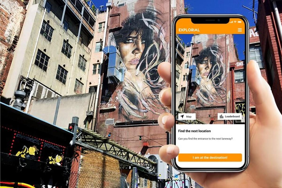 osoba držící mobilní telefon před budovou