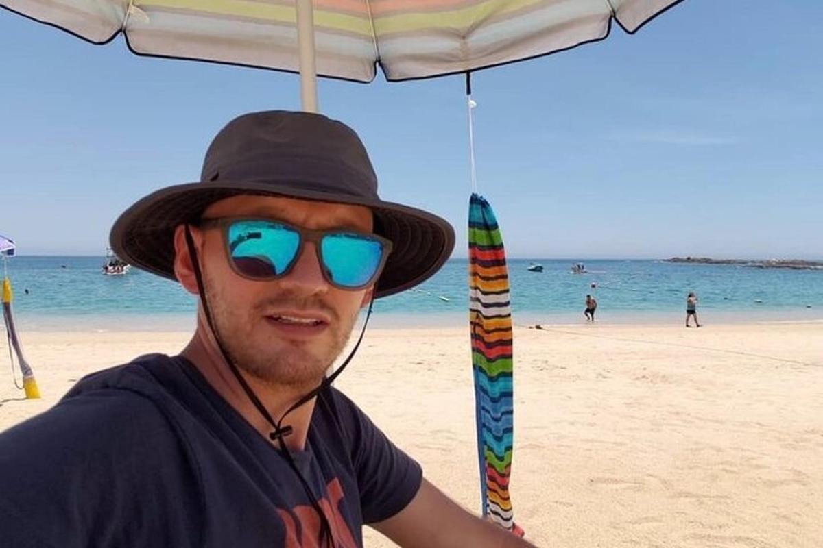 egy férfi napszemüveget és kalapot visel a strandon