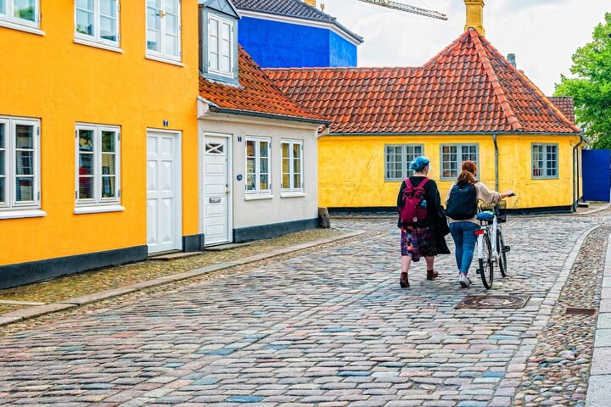 two women walking a bike in front of colorful houses