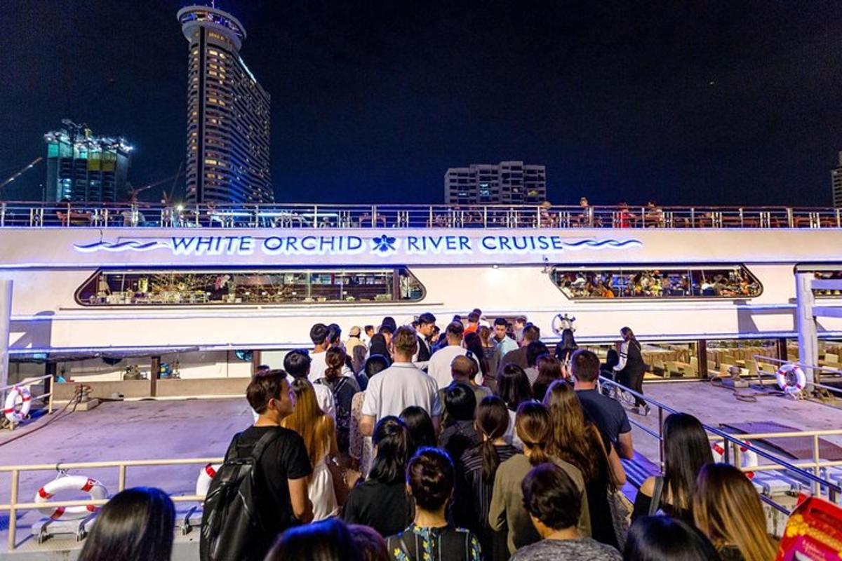 Una multitud de personas de pie en un crucero por la noche.