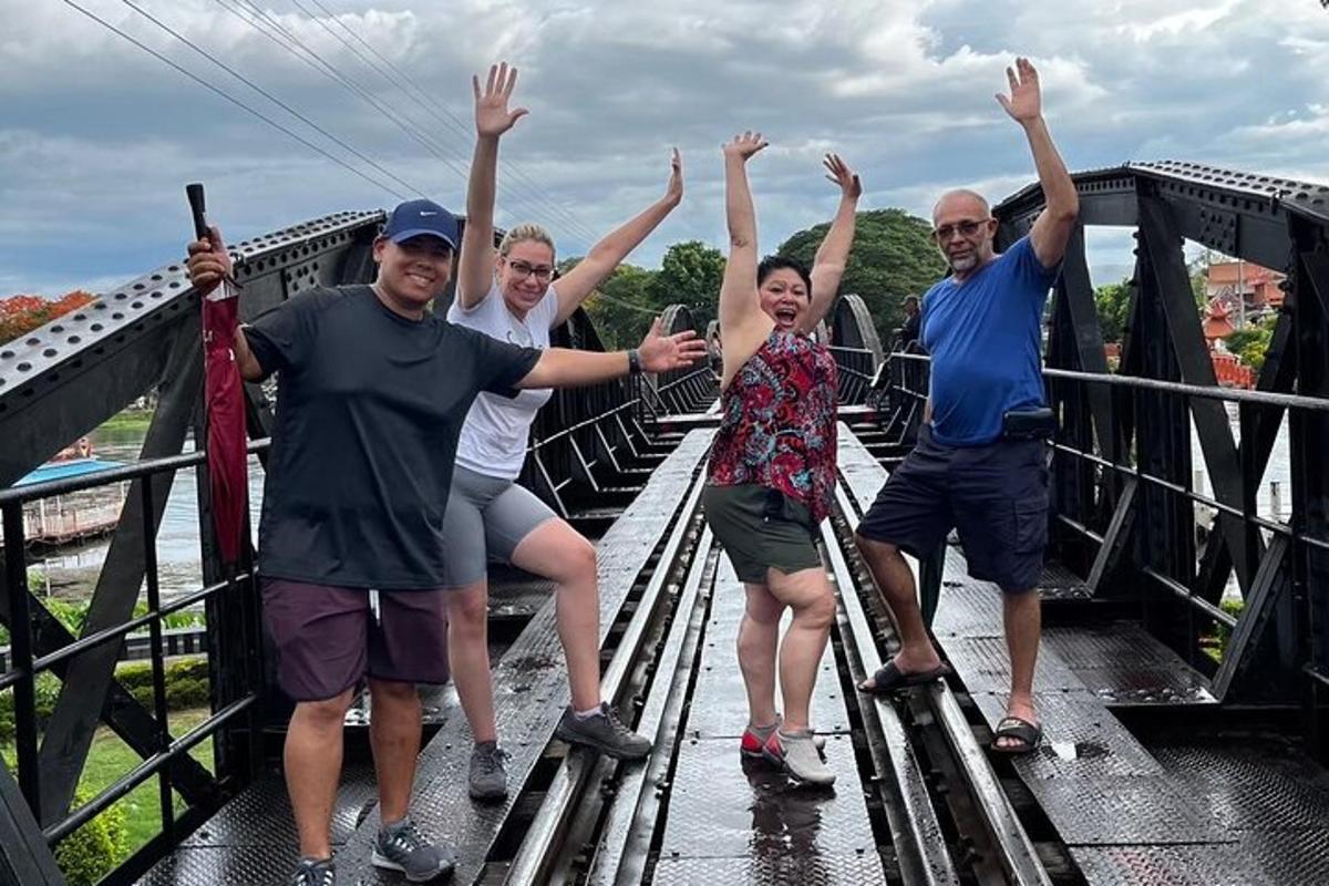 um grupo de pessoas em pé em uma ponte com as mãos para cima