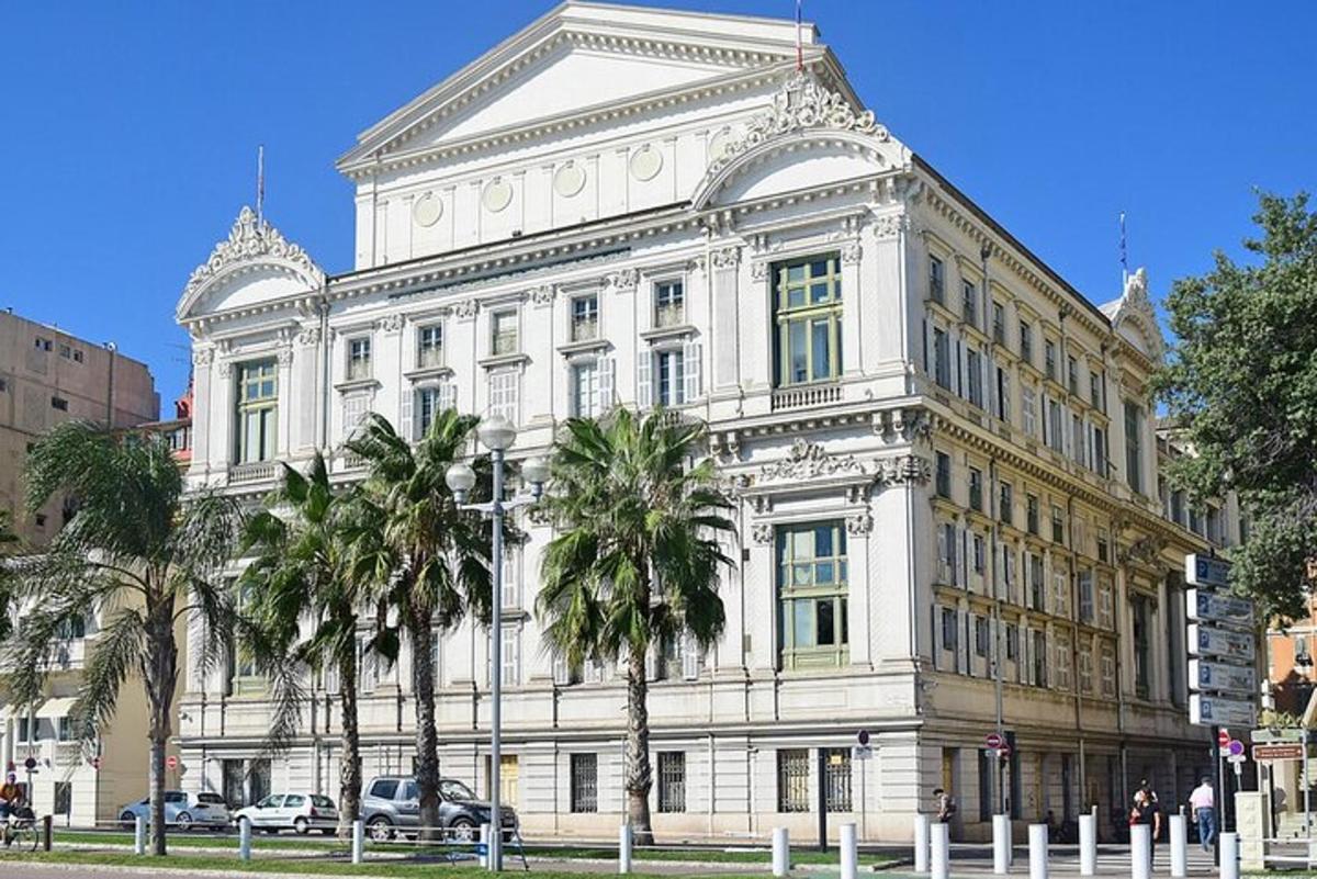 ένα μεγάλο λευκό κτίριο με φοίνικες μπροστά του