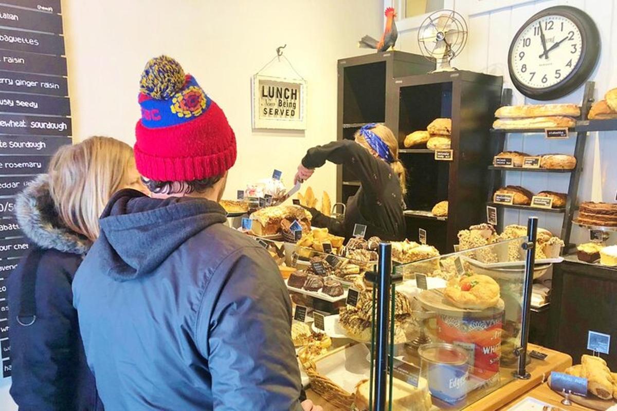 due persone in piedi al bancone di una panetteria che guardano i pasticcini
