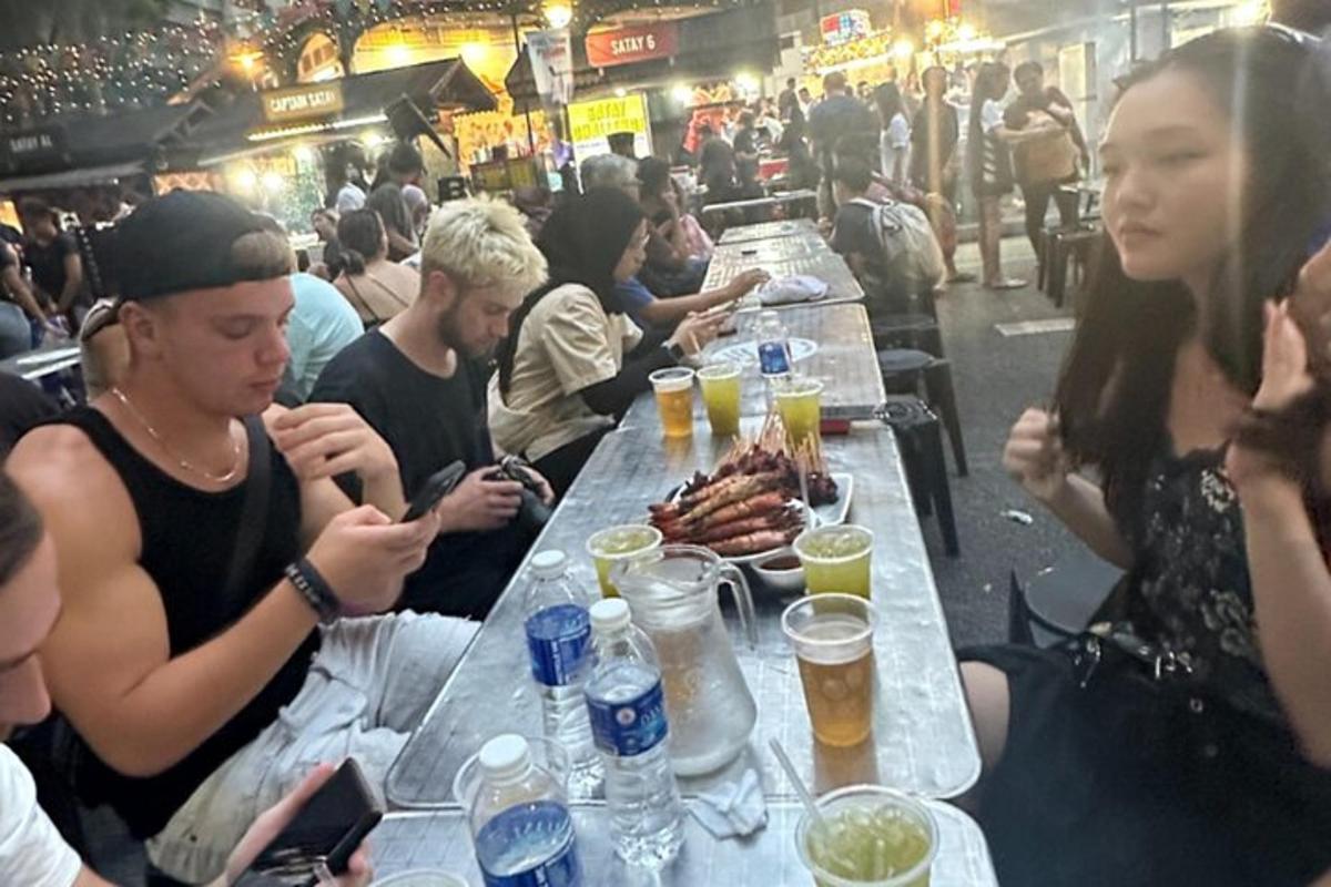 skupina lidí sedících u stolu s jídlem a pitím