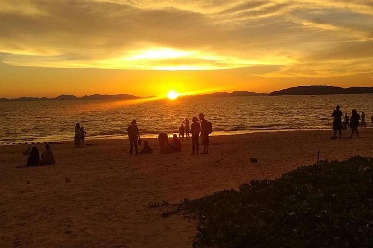 Un grupo de personas de pie en la playa al atardecer