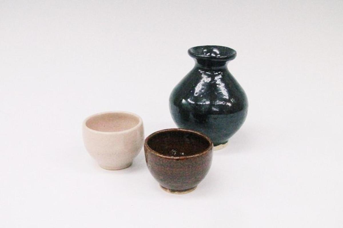 un vaso nero e due tazze su uno sfondo bianco