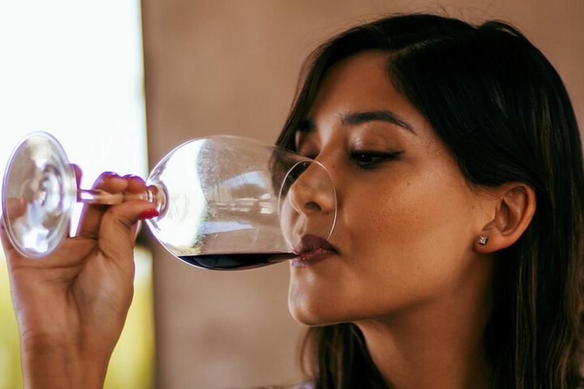 una mujer bebiendo una copa de vino tinto