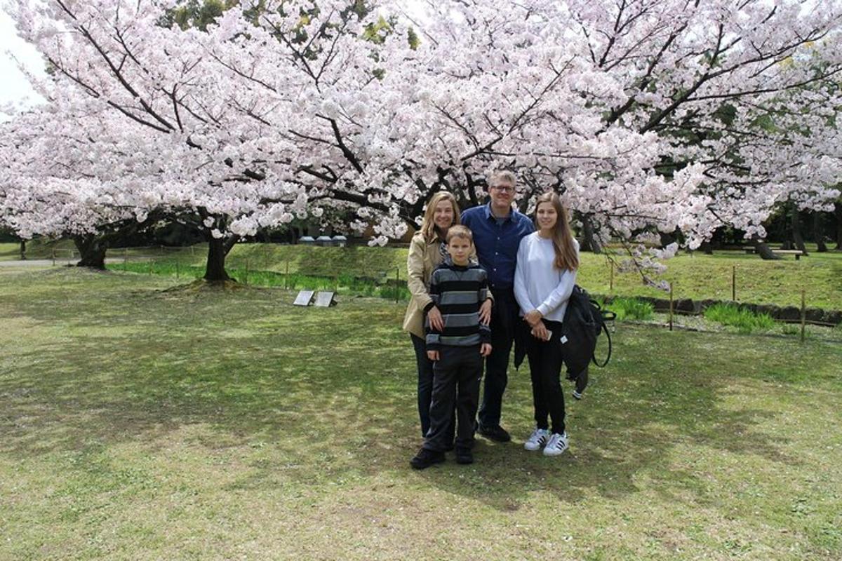 Una familia parada frente a un árbol con flores.
