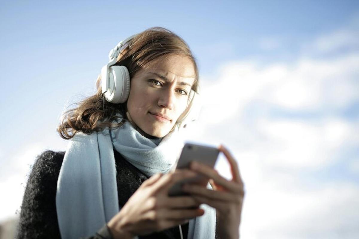 muž se sluchátky a dívá se na mobilní telefon