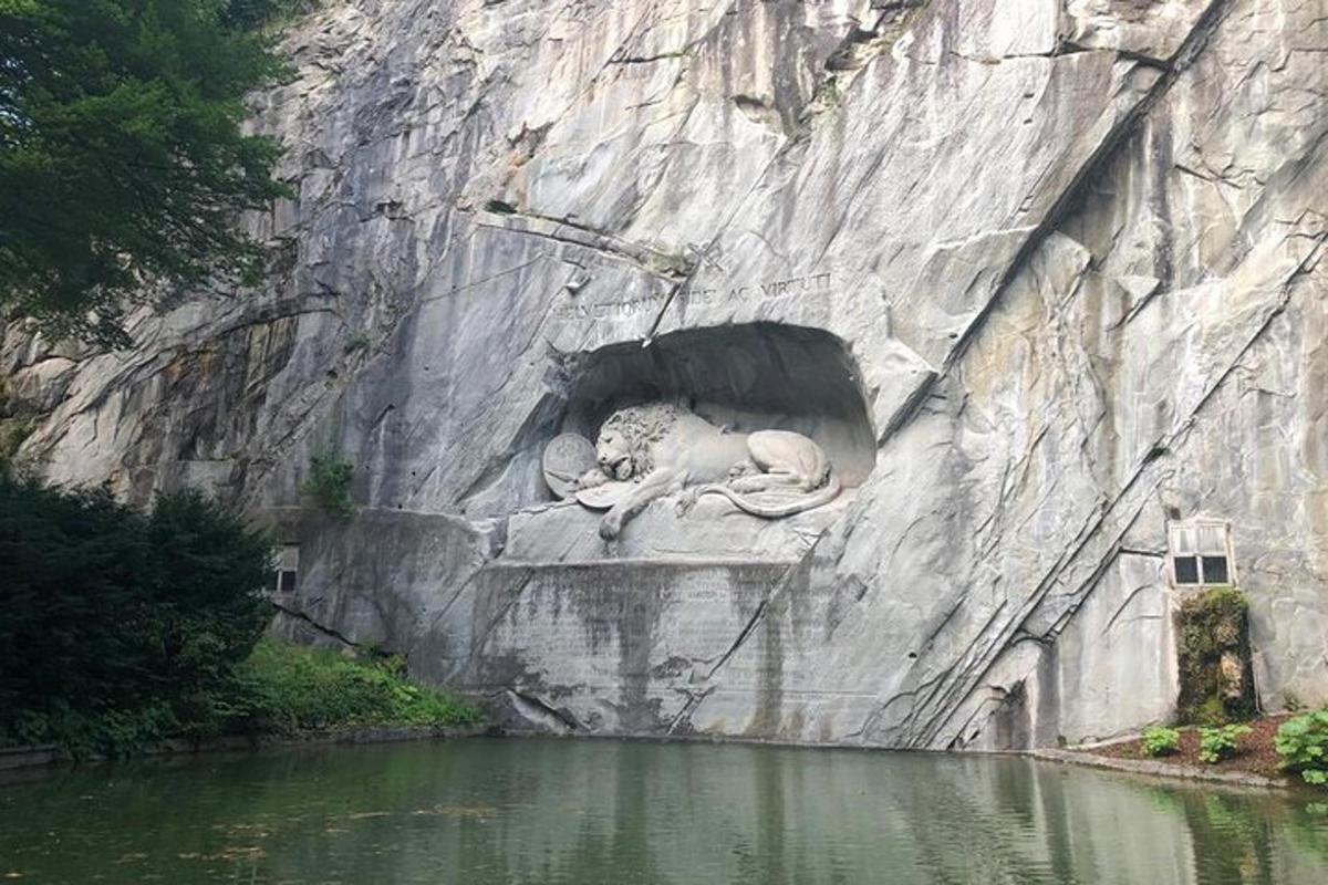 una statua di un leone su una parete rocciosa vicino all'acqua