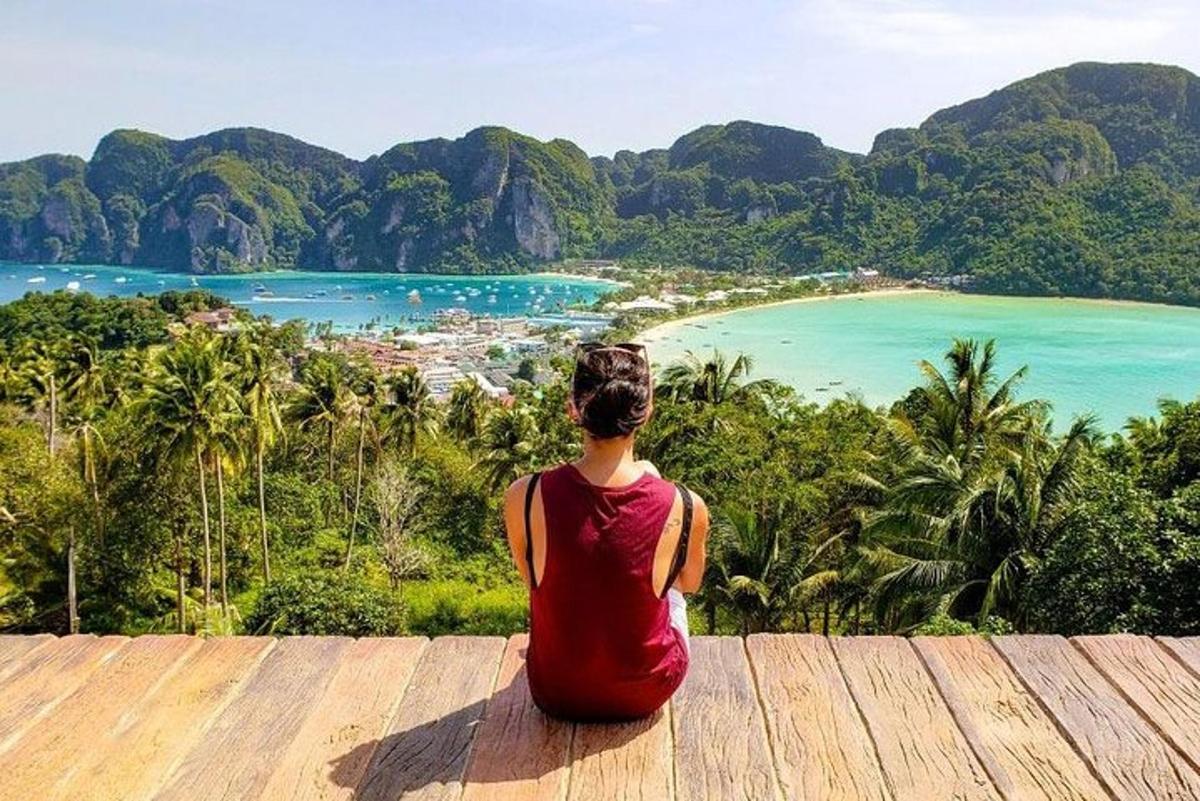 a woman sitting on a wooden deck looking at a beach