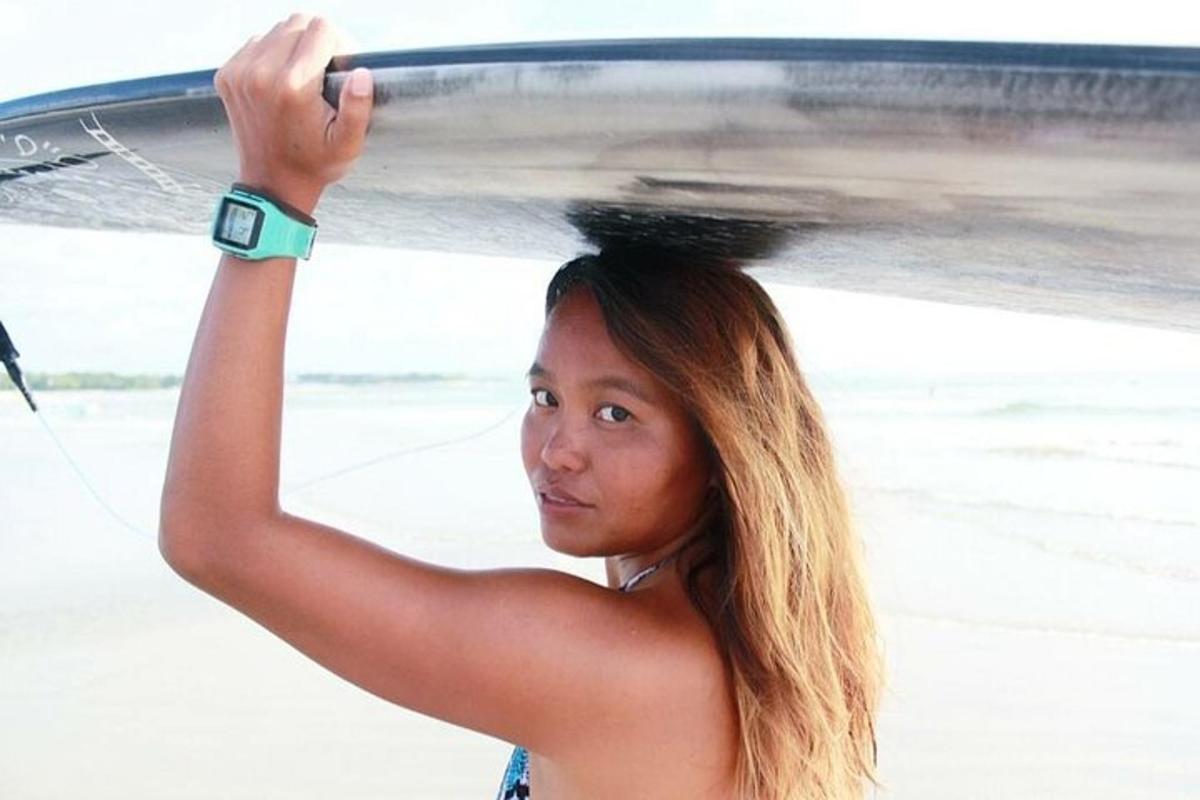 uma mulher está segurando uma prancha de surfe na cabeça
