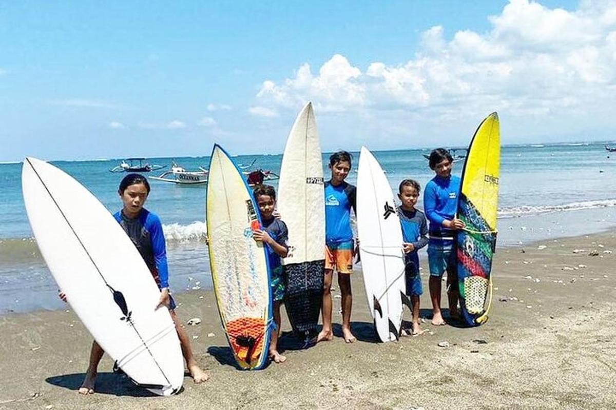 um grupo de crianças em pé na praia segurando pranchas de surfe