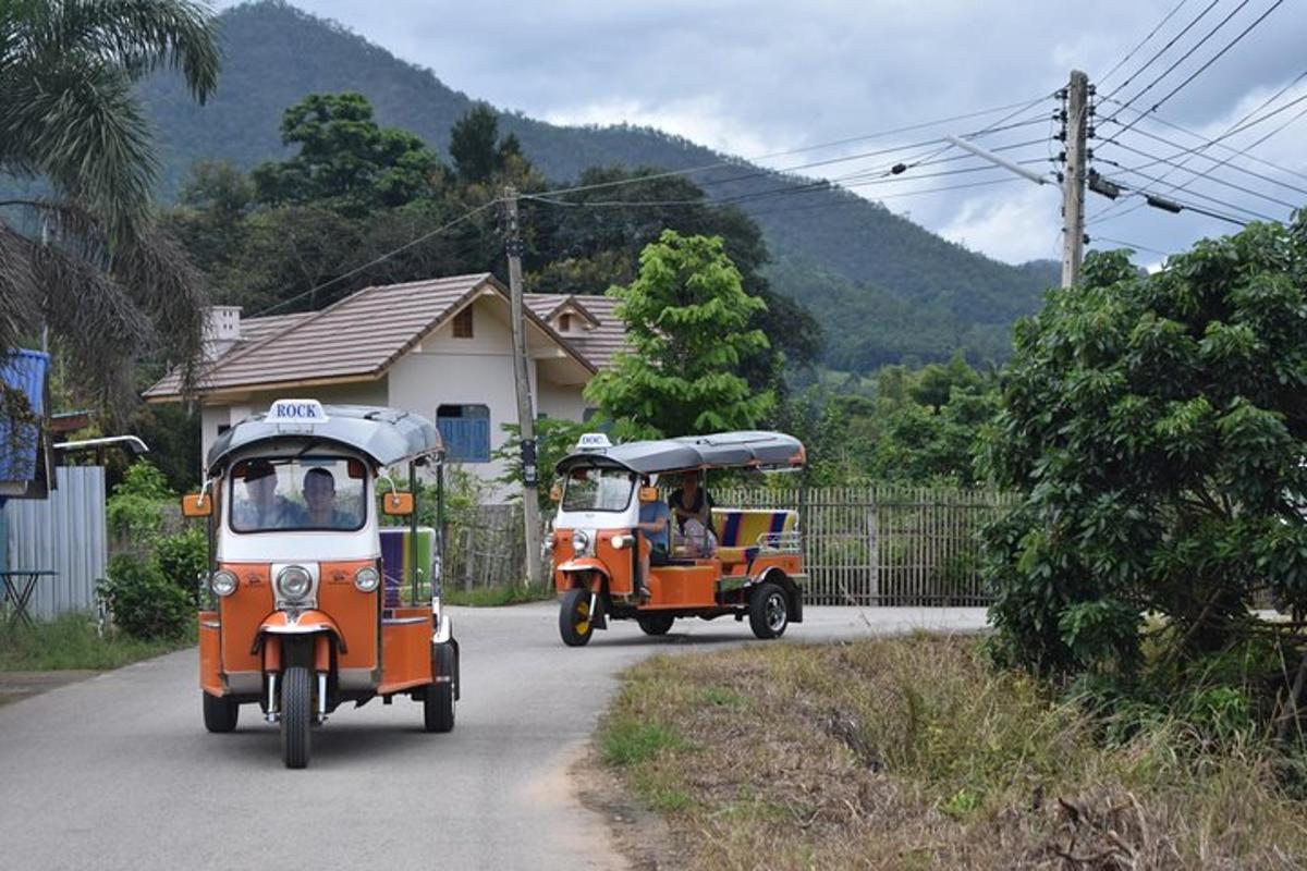 dua tuk tuk memandu di jalan raya di sebelah kereta