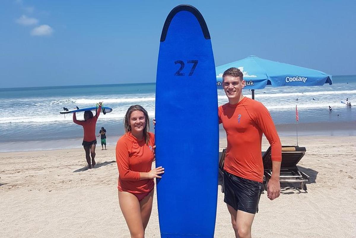 seorang pria dan wanita memegang papan selancar biru di pantai