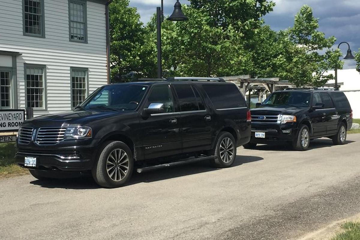 two black trucks parked on a street next to a house