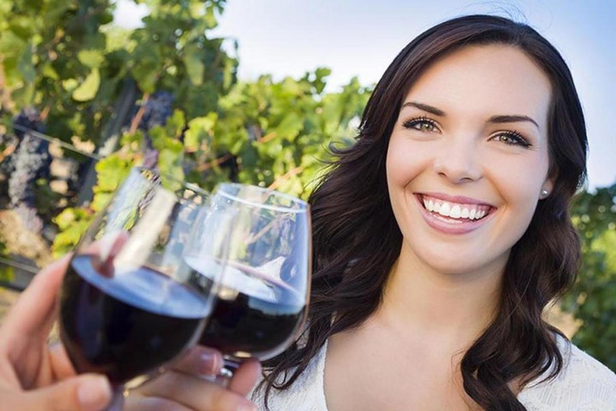 a woman holding two glasses of red wine