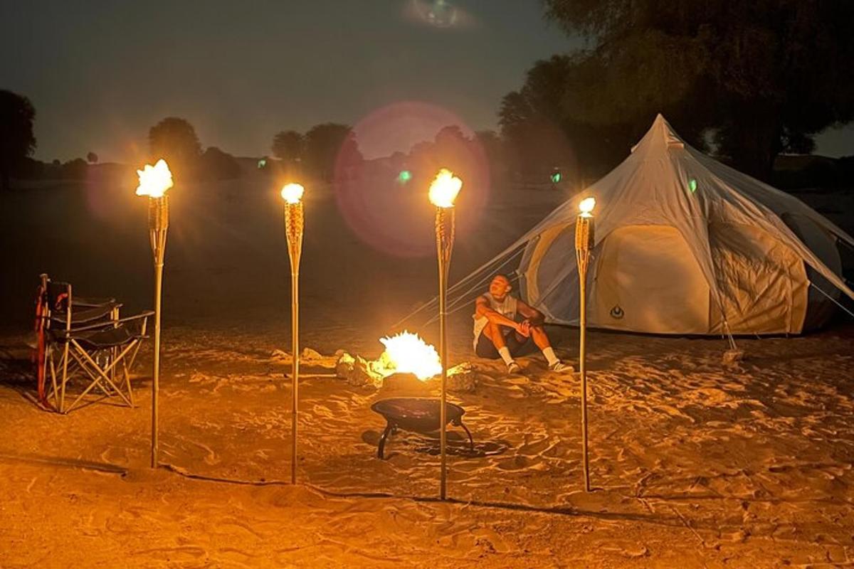 a man sitting in front of a tent with torches