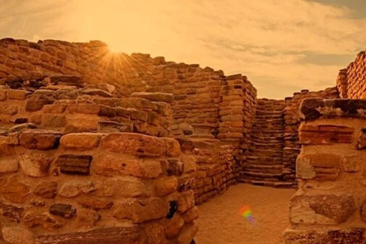 a stone wall with the sun setting behind it