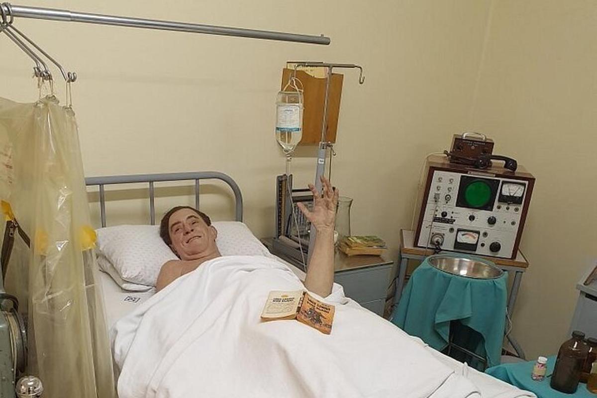 a man laying in a hospital bed holding up a bottle