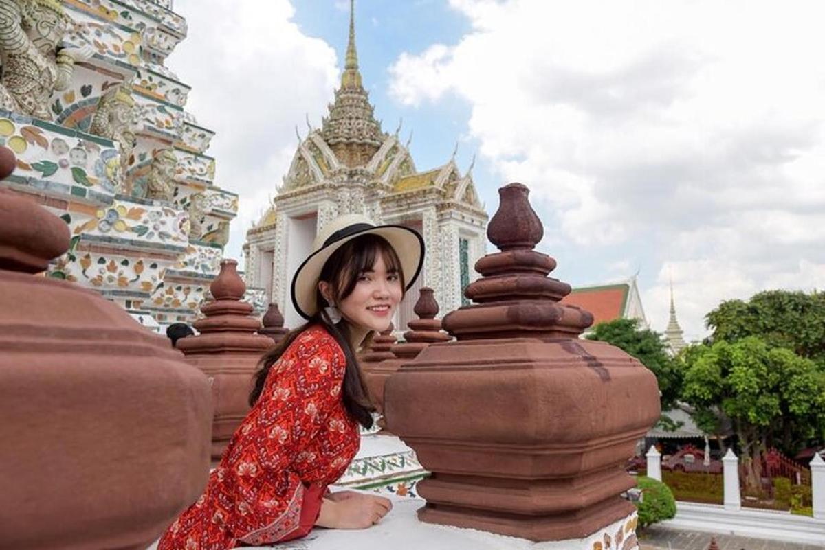 một người phụ nữ mặc váy đỏ và đội mũ đang ngồi trước một tòa nhà