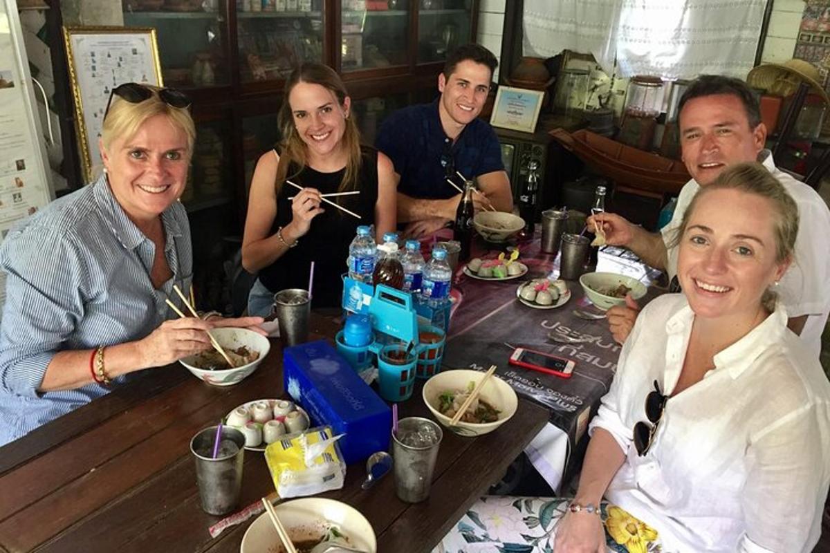 un gruppo di persone sedute attorno a un tavolo che mangiano noodles