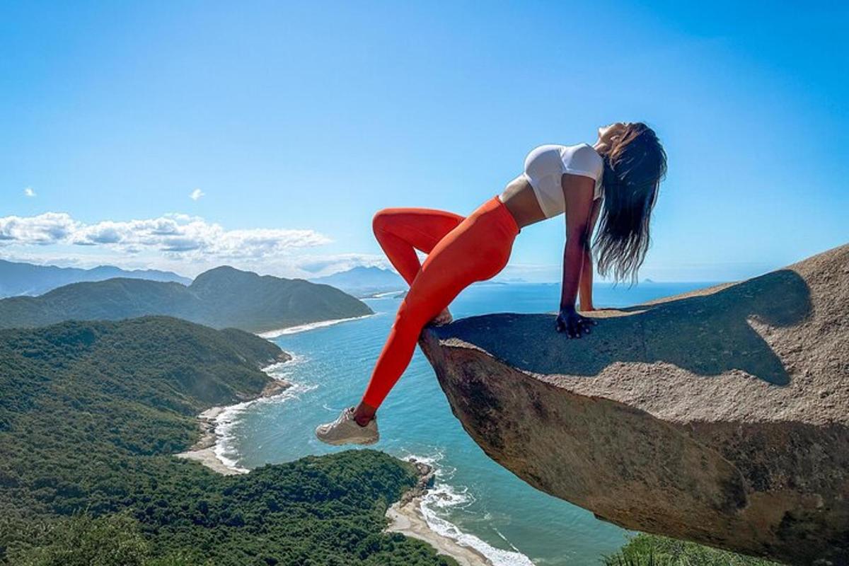 a woman is standing on the side of a rock