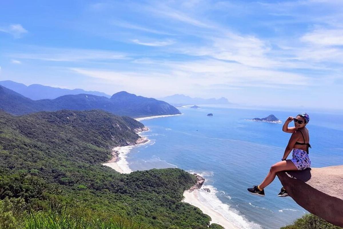 a woman sitting on the edge of a cliff overlooking the ocean