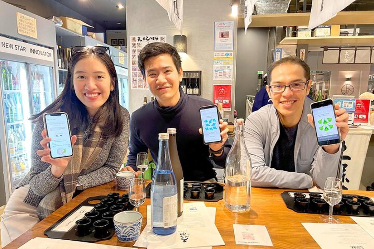 tre persone che tengono in mano il loro cellulare appoggiato a un tavolo