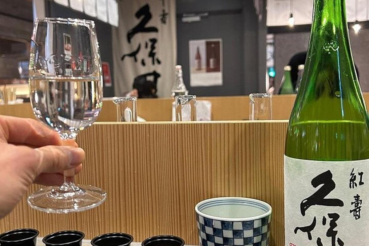 una persona che tiene un bicchiere di vino accanto a una bottiglia di vino