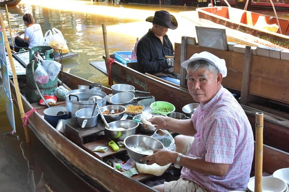 un uomo seduto su una barca che prepara il cibo