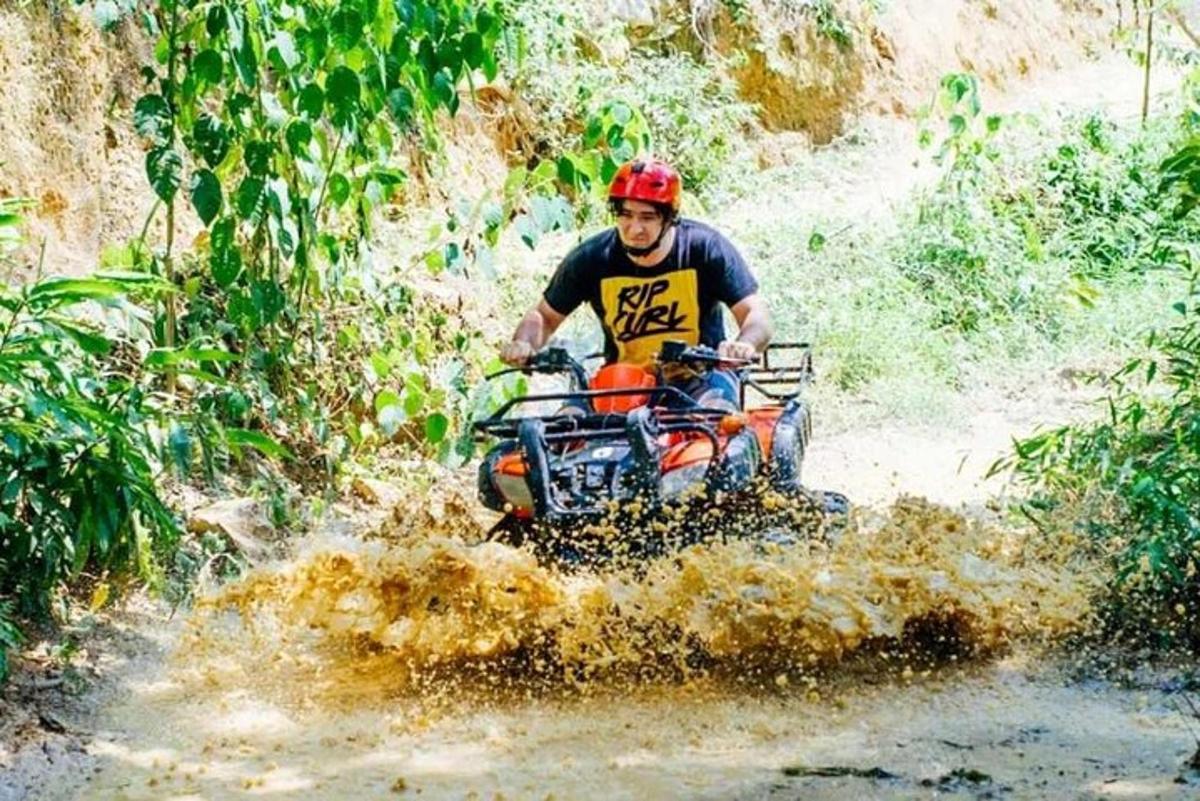 một người đàn ông đang lái xe bốn bánh qua một con đường lầy lội
