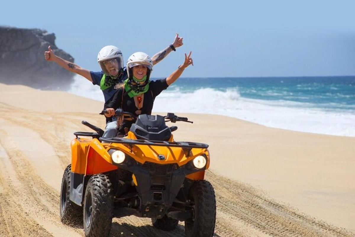 duas pessoas andando de quadriciclo na praia