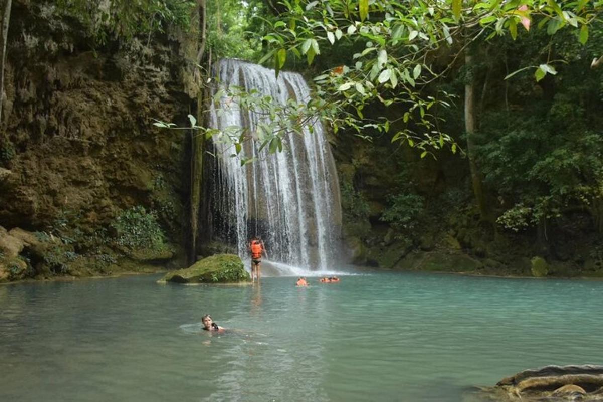 um grupo de pessoas na água em frente a uma cachoeira